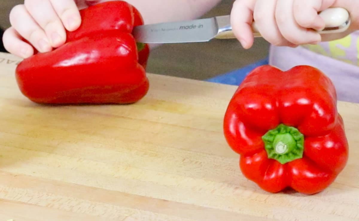 Kaia is cutting the tops off of bell peppers