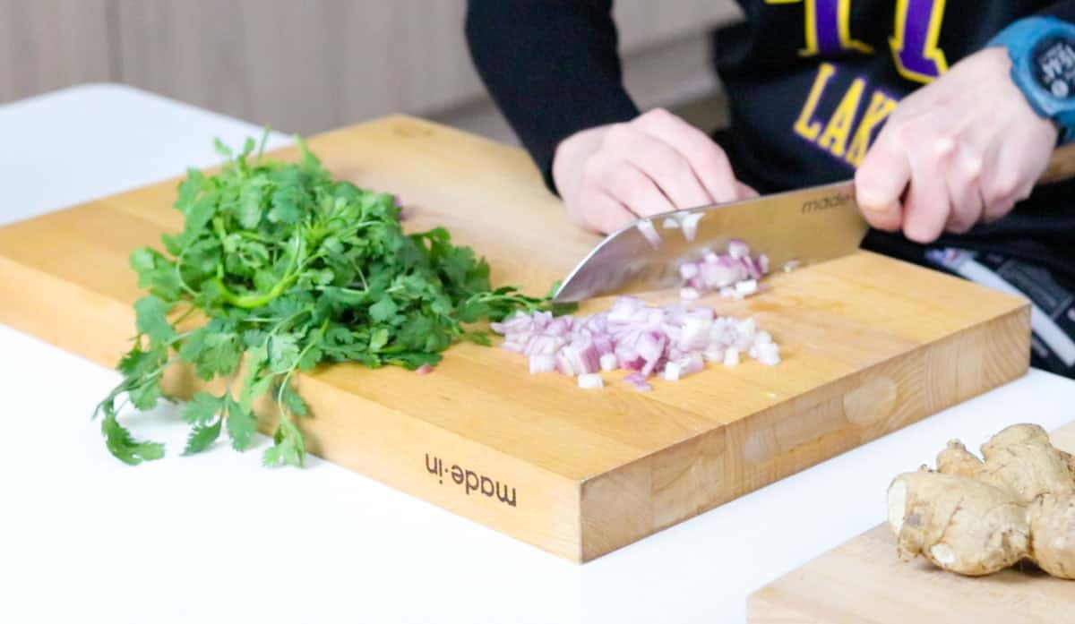 Kristin is chopping a shallot with a Santoku knife and butcher block