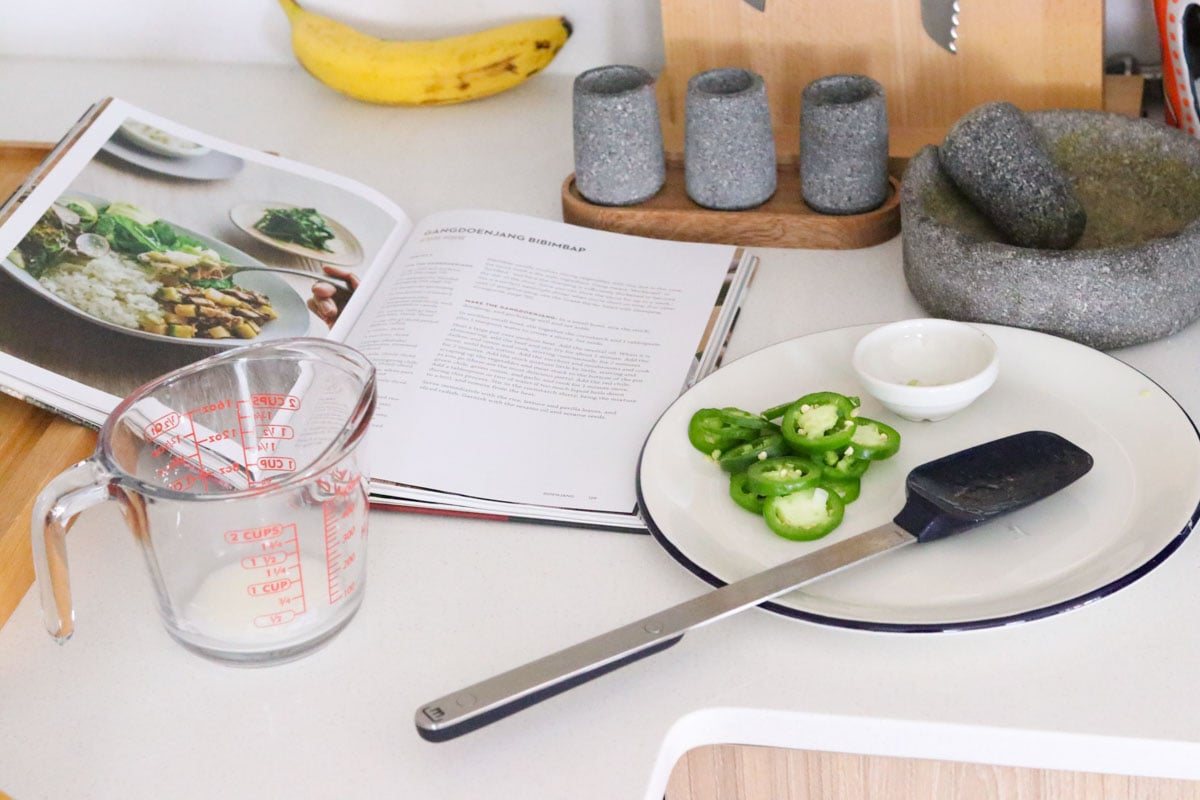 sliced jalapeño peppers on a plate beside jang cookbook