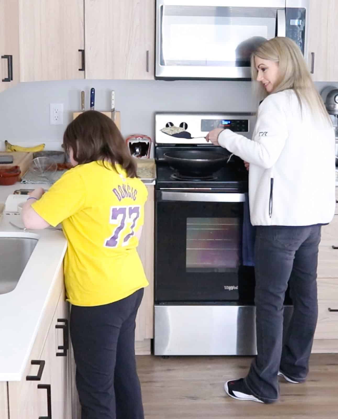 Kaia is whisking eggs at the counter and talking to Kristin