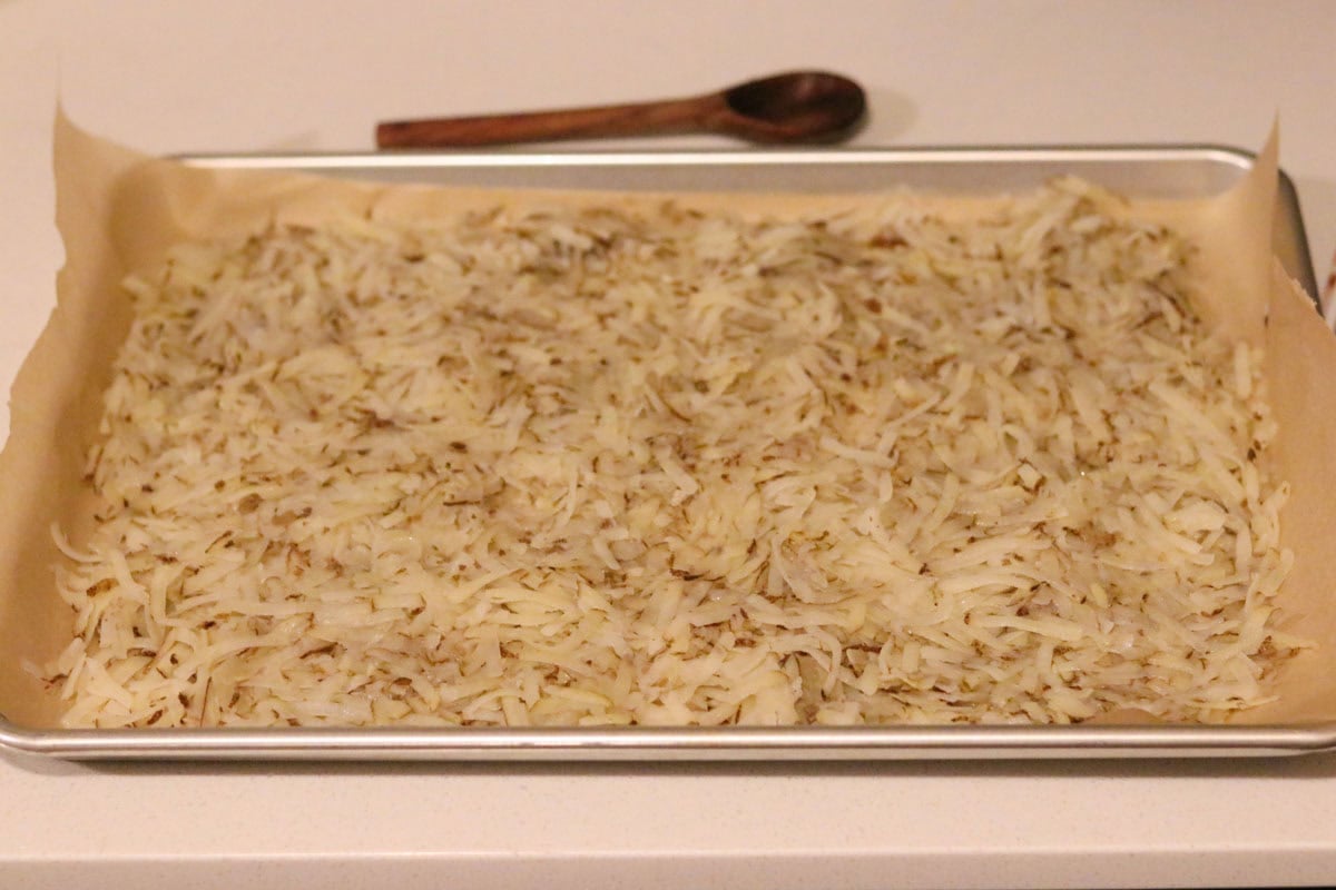shredded potatoes on a baking sheet with parchment paper