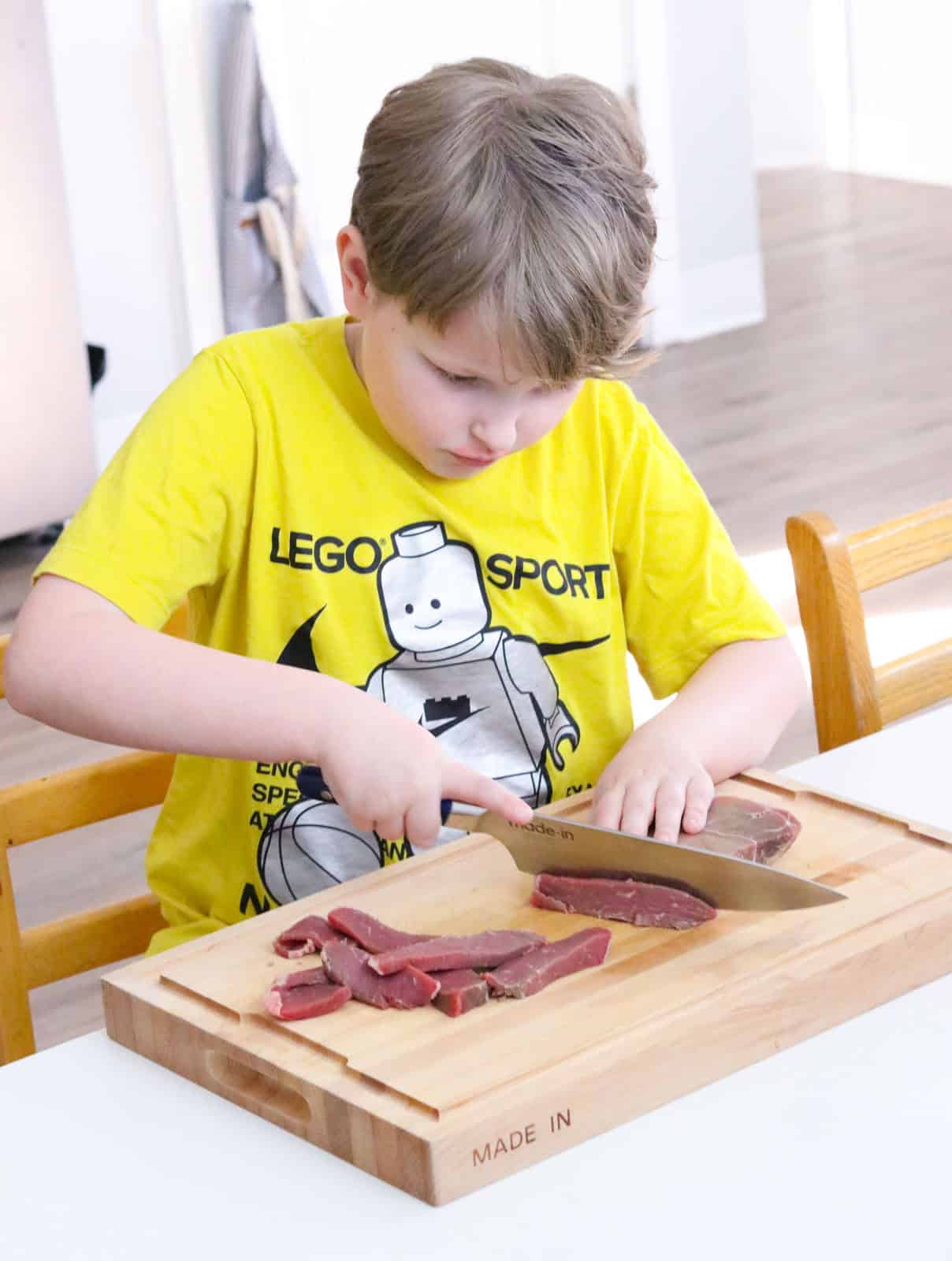 Noah is slicing beef shoulder with a chef knife
