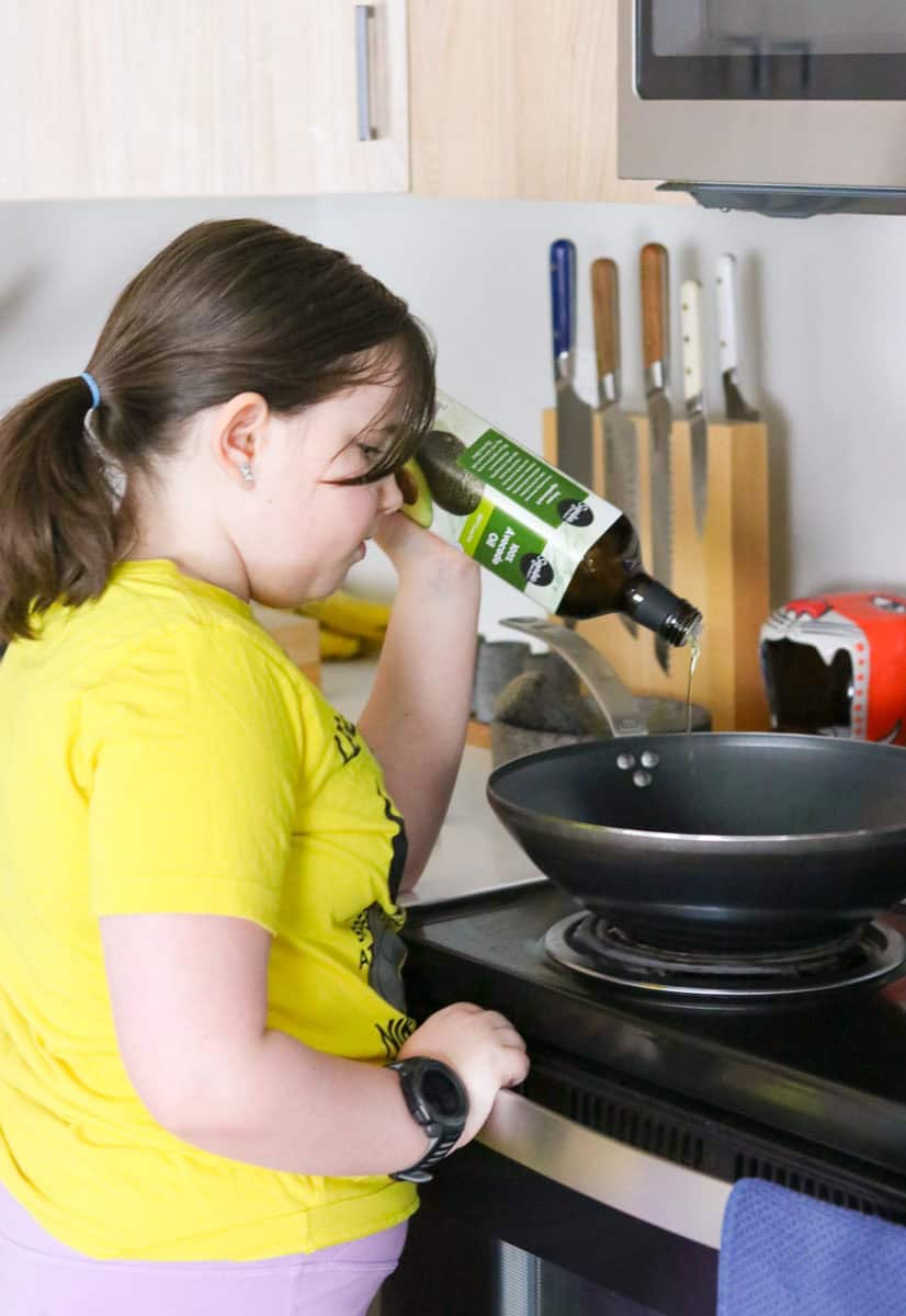 Kaia is adding oil to a wok