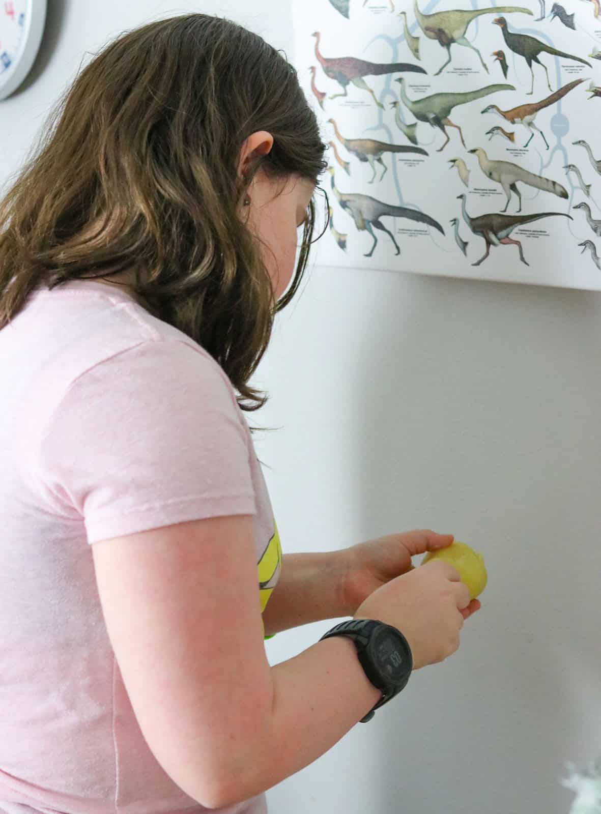 Kaia is peeling potatoes over the trash can