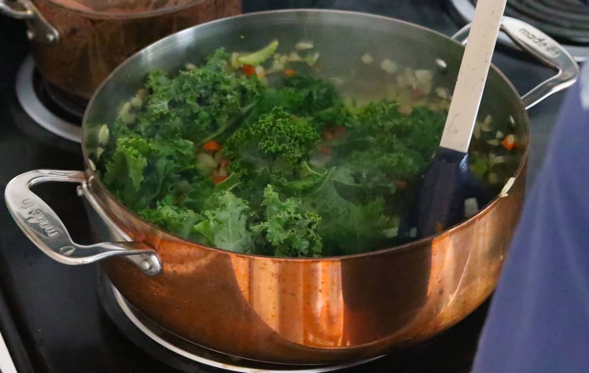 Katalina is stirring kale into pizza beans ingredients