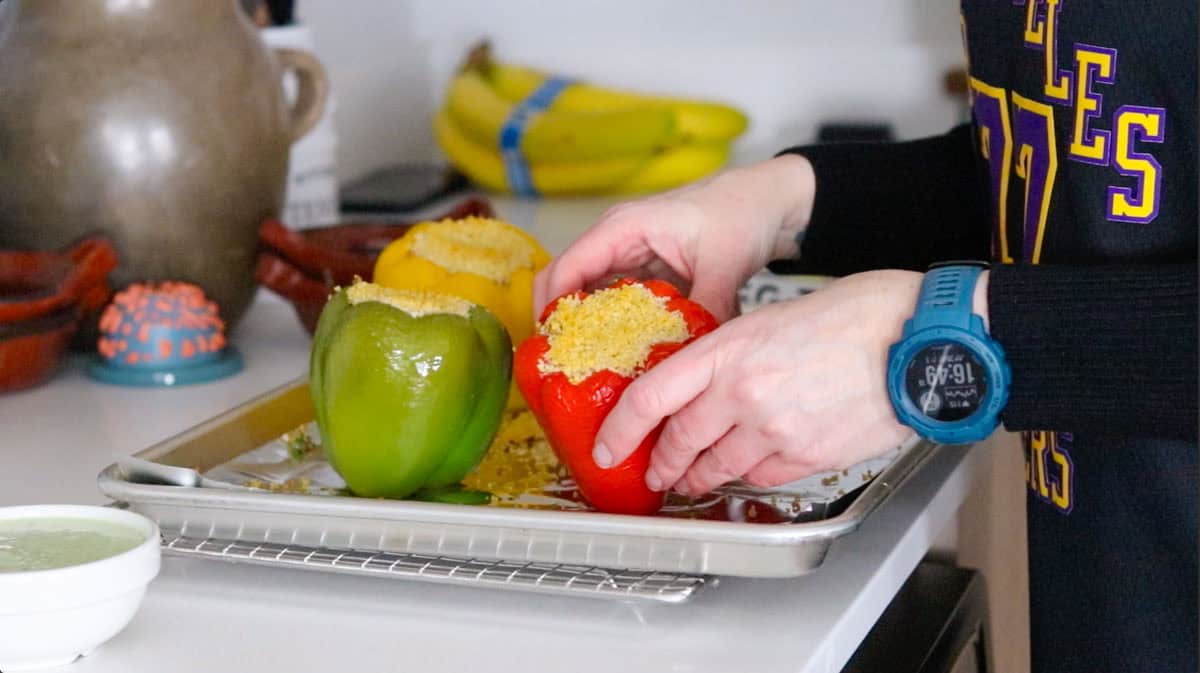 Kristin is positioning stuffed bell peppers on a baking sheet