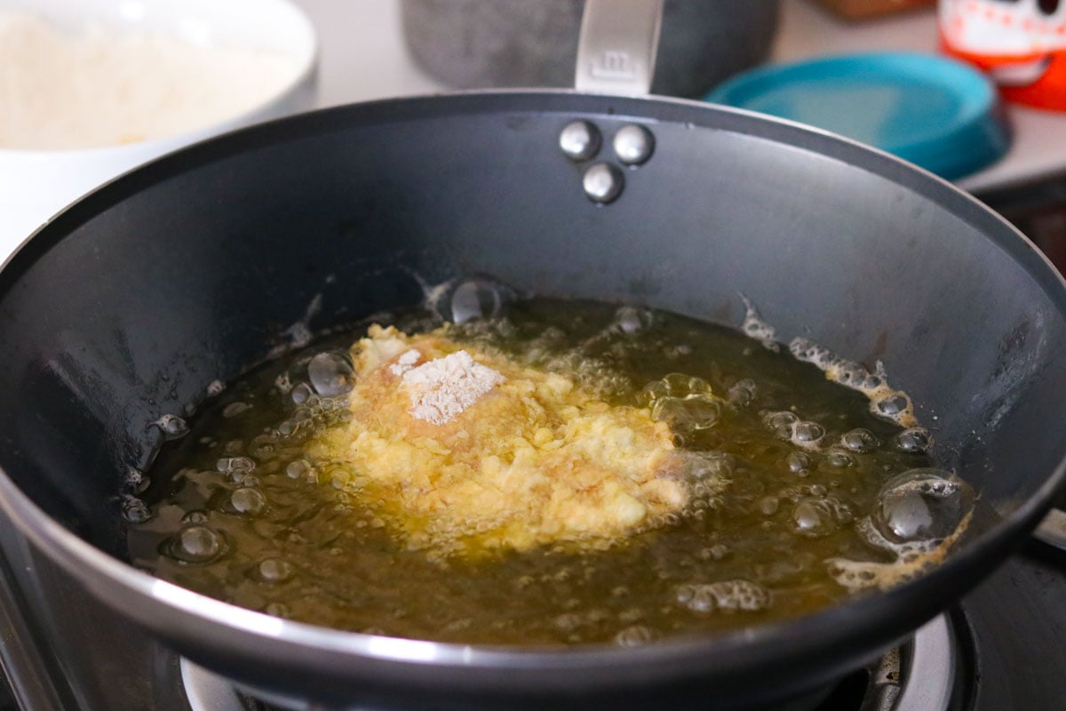 breaded chicken thighs frying in a wok