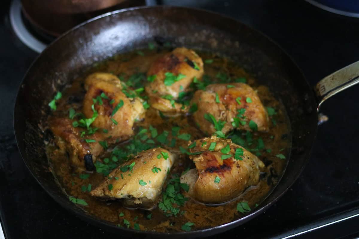chicken thighs in mustard-mushroom sauce in a carbon steel pan