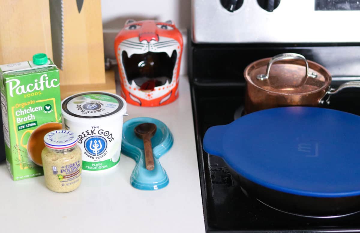 mustard sauce ingredients beside a Made In carbon steel pan with a cover
