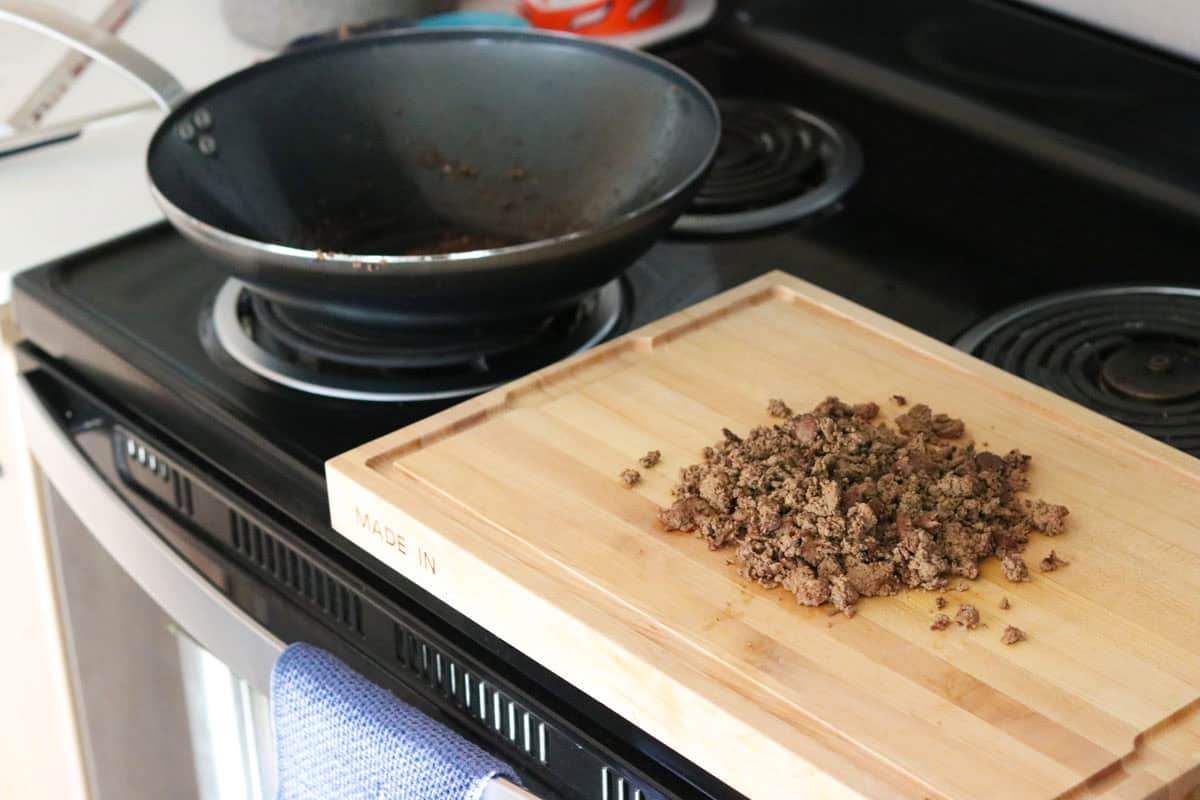 cooked chicken livers on a butcher block beside a wok