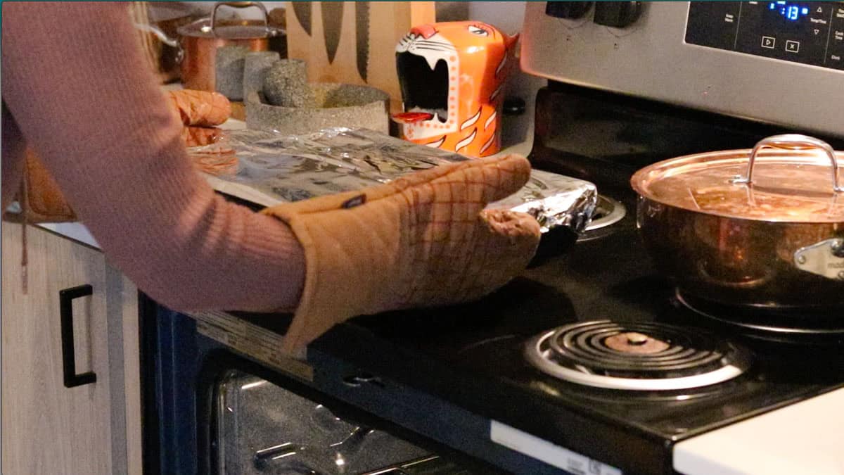 Kristin is holding a baking dish covered with aluminum foil