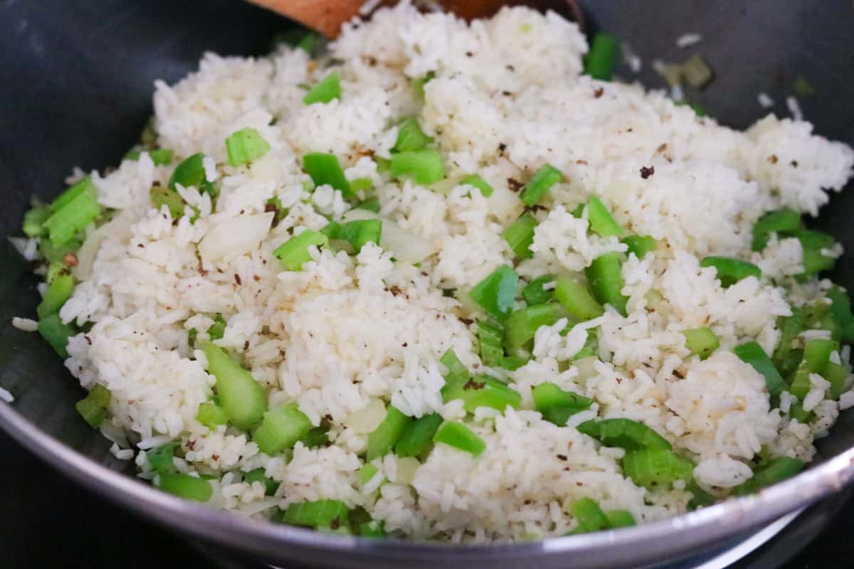 day-old rice frying in a wok with celery, onion, and green pepper