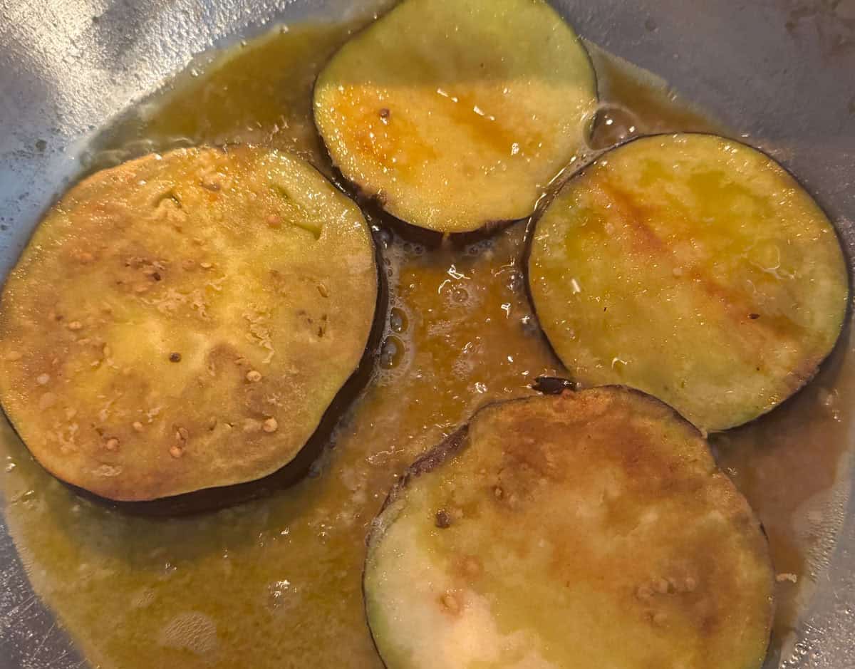 eggplant slices frying in oil in a saucier