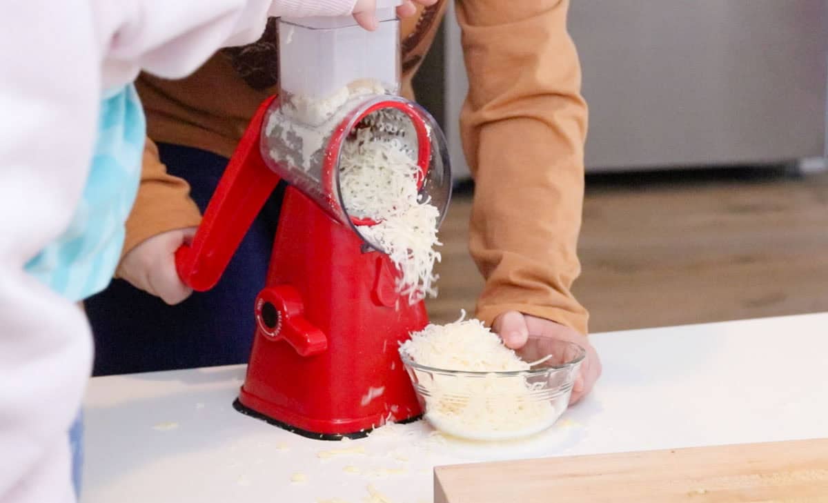 Noah and Kaia are grating cheese with a NutriSlicer