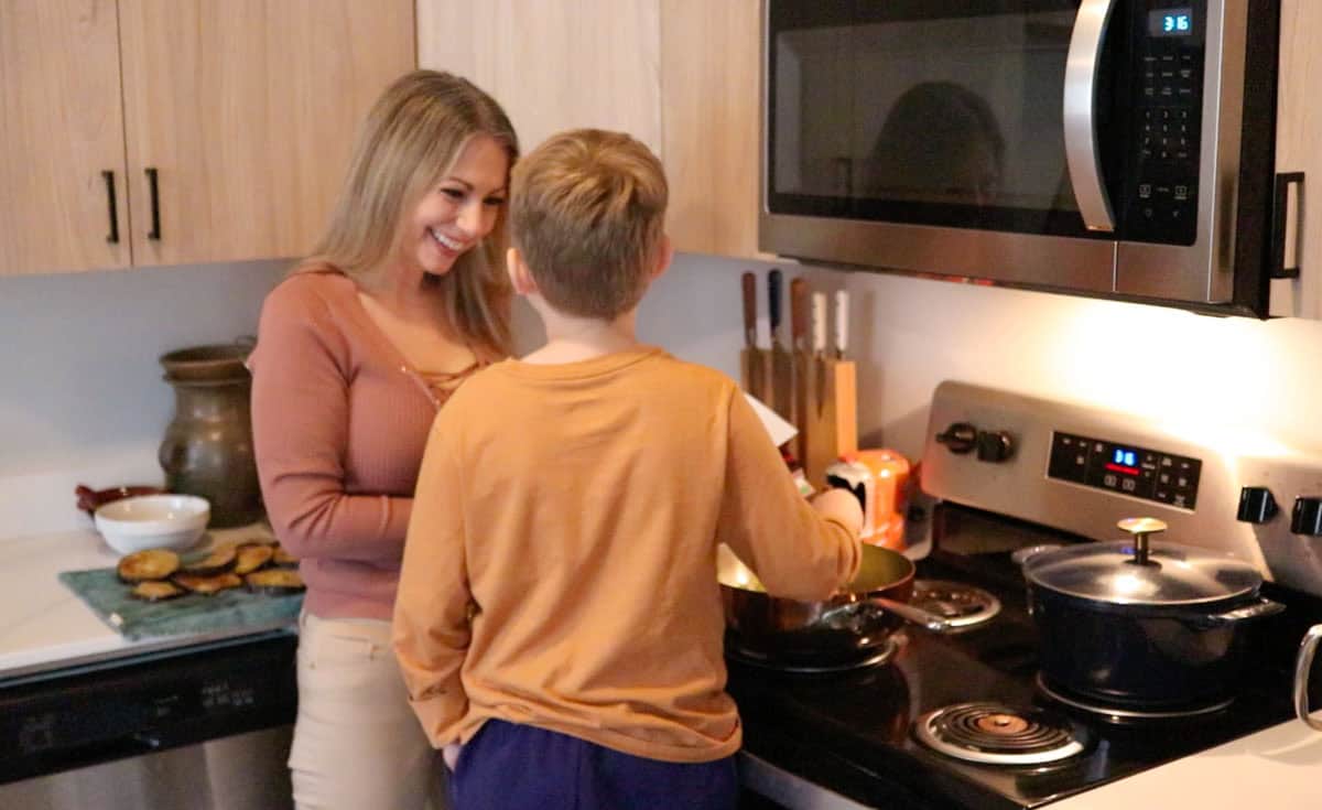 Kristin and Noah are joking around at the stove