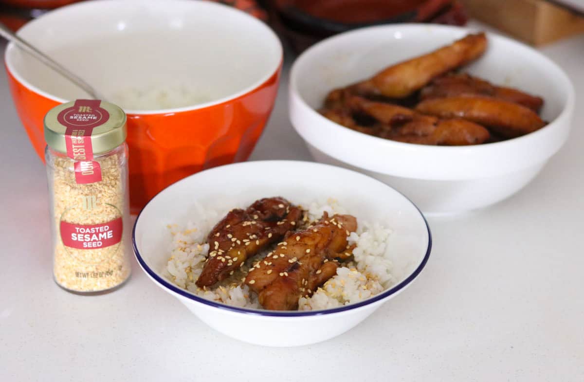 Korean Chicken Teriyaki in a bowl beside toasted sesame seeds