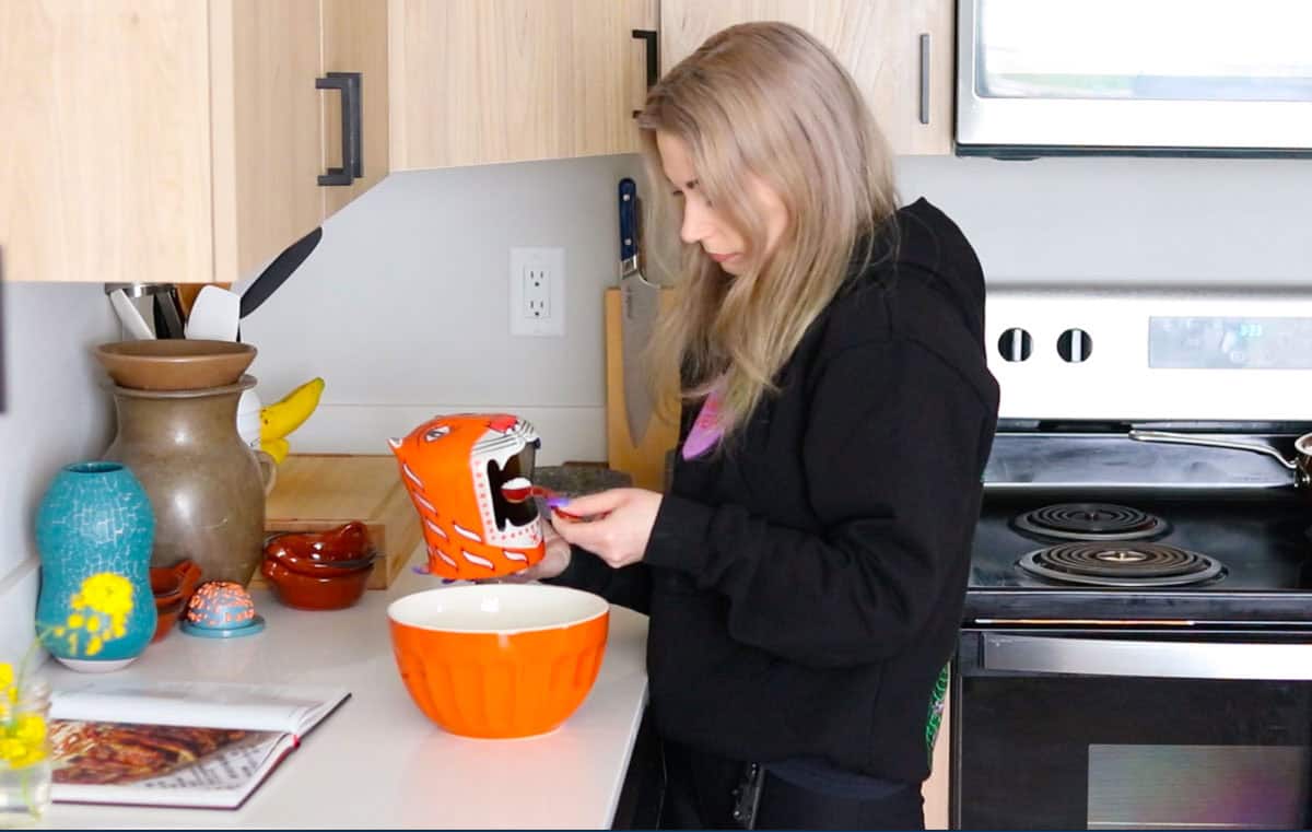 Kristin is adding salt from a salt tiger to a bowl with marinade ingredients