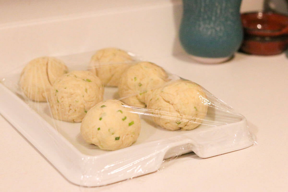 dough balls on a baking slab covered with plastic wrap