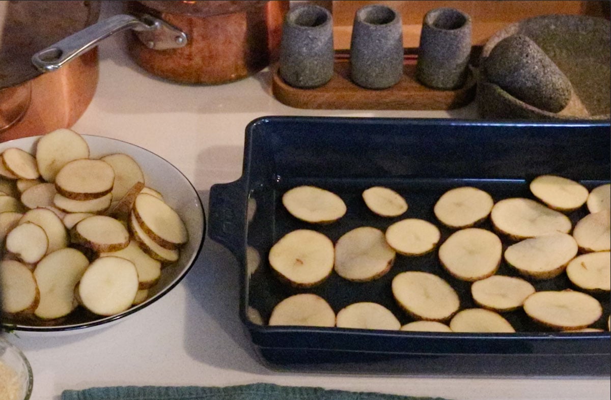 first layer of musaka (potato slices) in a baking dish