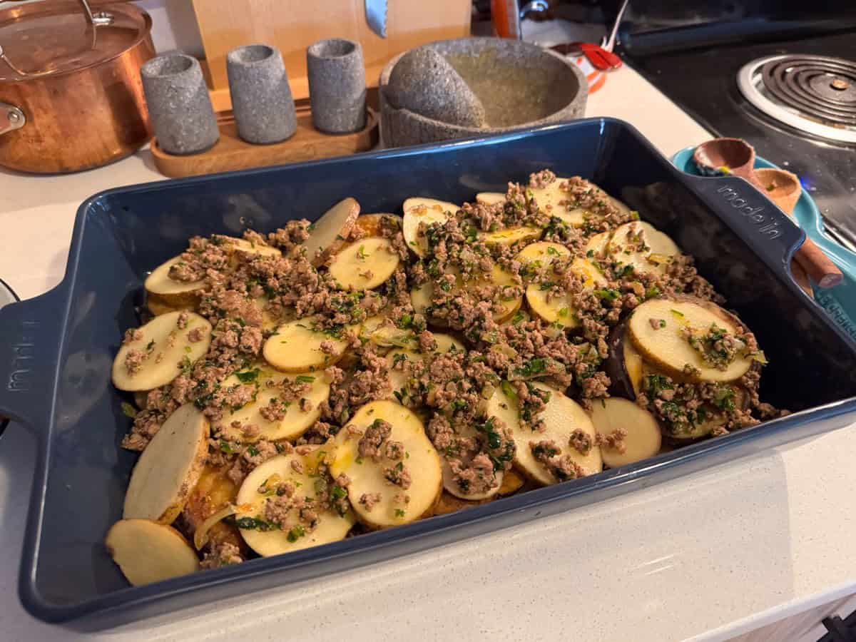 layers of eggplant, meat, and potatoes in a large rectangular baking dish