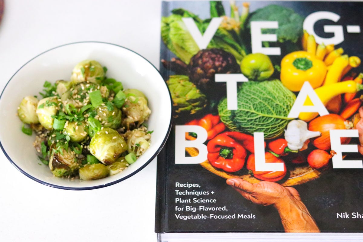 sweet and sticky brussels sprouts beside veg-table cookbook