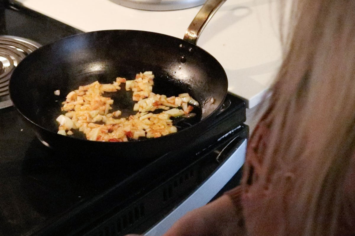onions and paprika cooking in a carbon steel pan