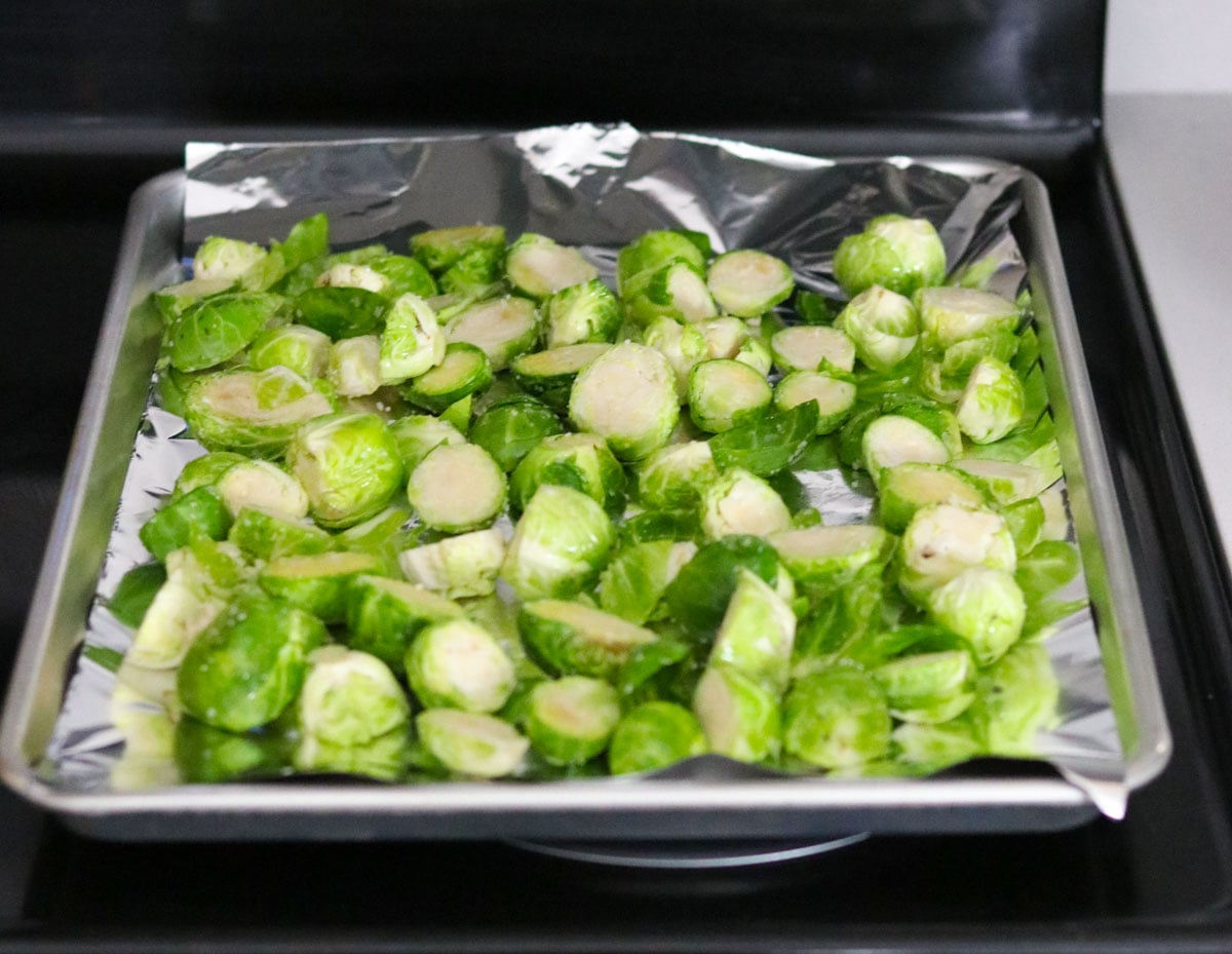 Brussels sprouts spread out on a sheet pan with aluminum foil