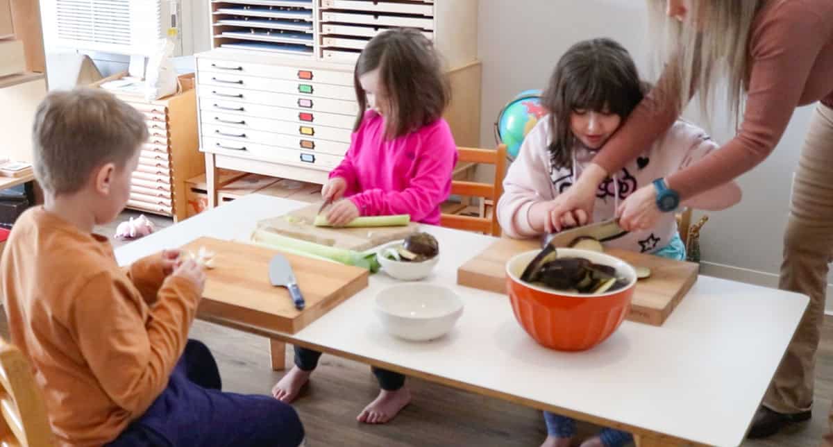 Kristin is showing Kaia how to use a Santoku knife with proper technique