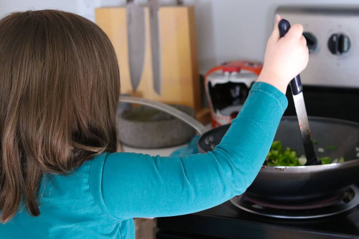 Katalina is stirring dirty rice ingredients with a spoonula