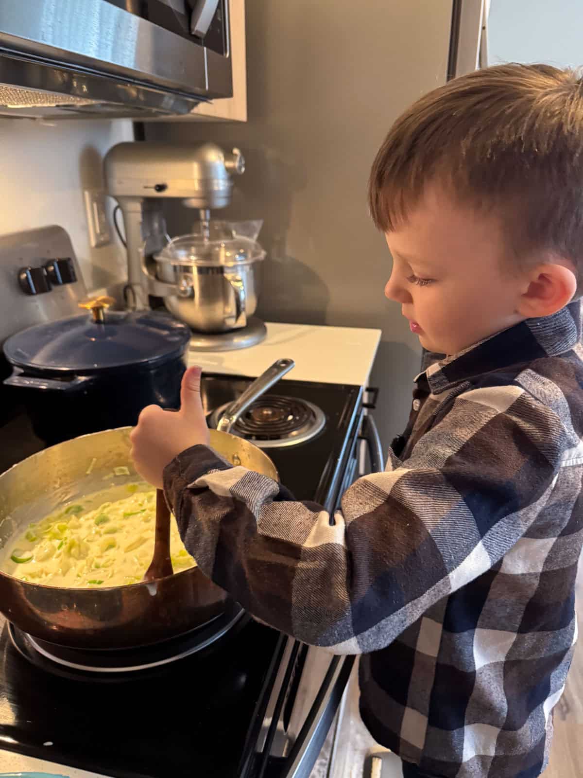 John is stirring a musaka cheese sauce with a wooden spoon