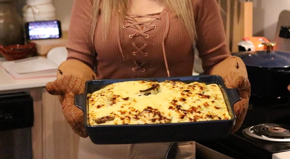 Kristin is holding The Ultimate Musaka and there's a basketball game on in the background