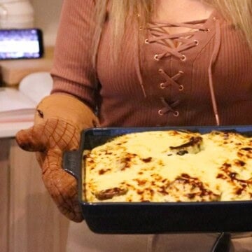 Kristin is holding The Ultimate Musaka and there's a basketball game on in the background