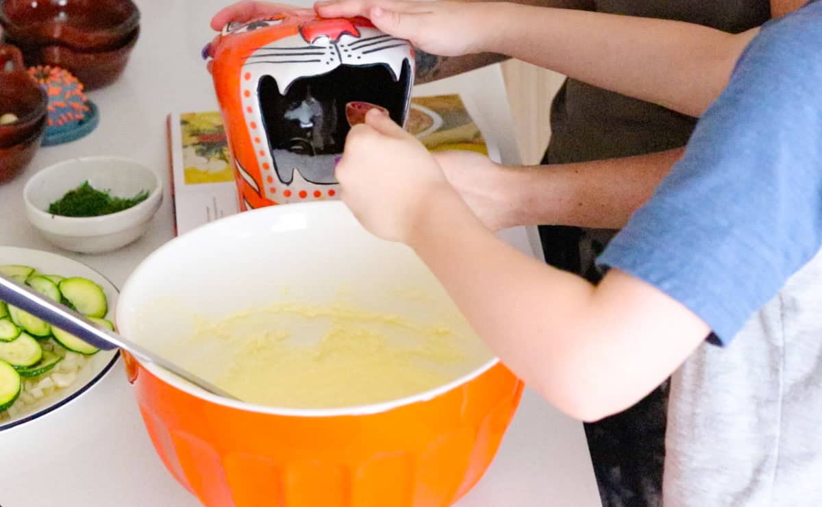 John is adding salt from a salt tiger to his bowl of ingredients