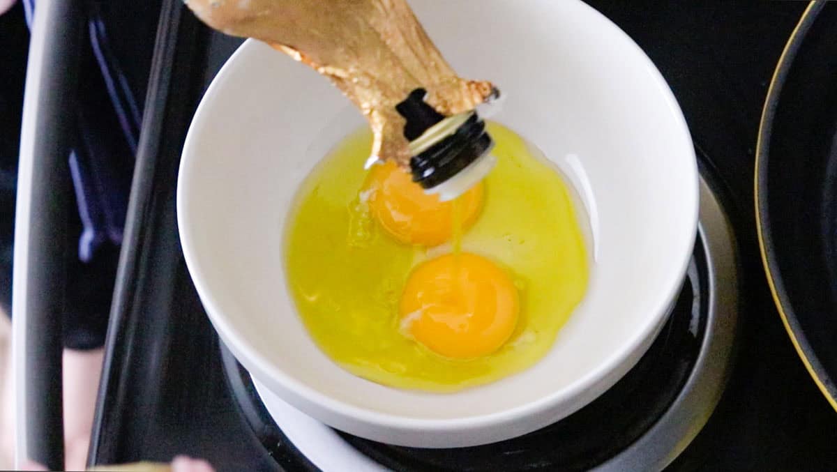 Kristin is combining olive oil and egg yolks in a bowl