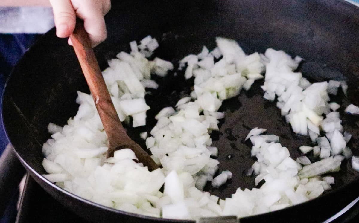 onions cooking in a pan while John stirs