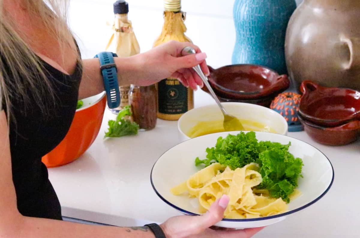 Kristin is adding Caesar dressing to kale