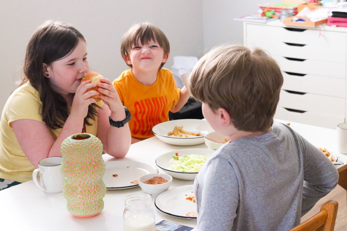 the kids are eating the miso-masala fried chicken sando from Mother Tongue and John is making a funny face for the camera