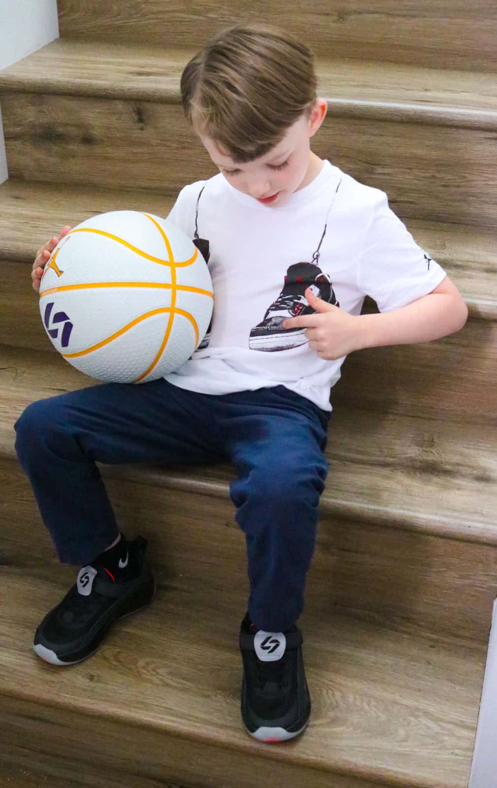 John is pointing to the Jordans on his t-shirt and holding a basketball