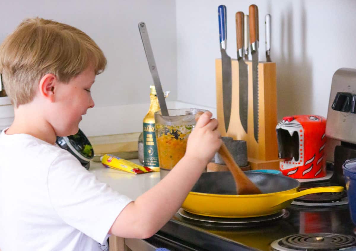 Noah is stirring sofrito in an enameled cast-iron pan