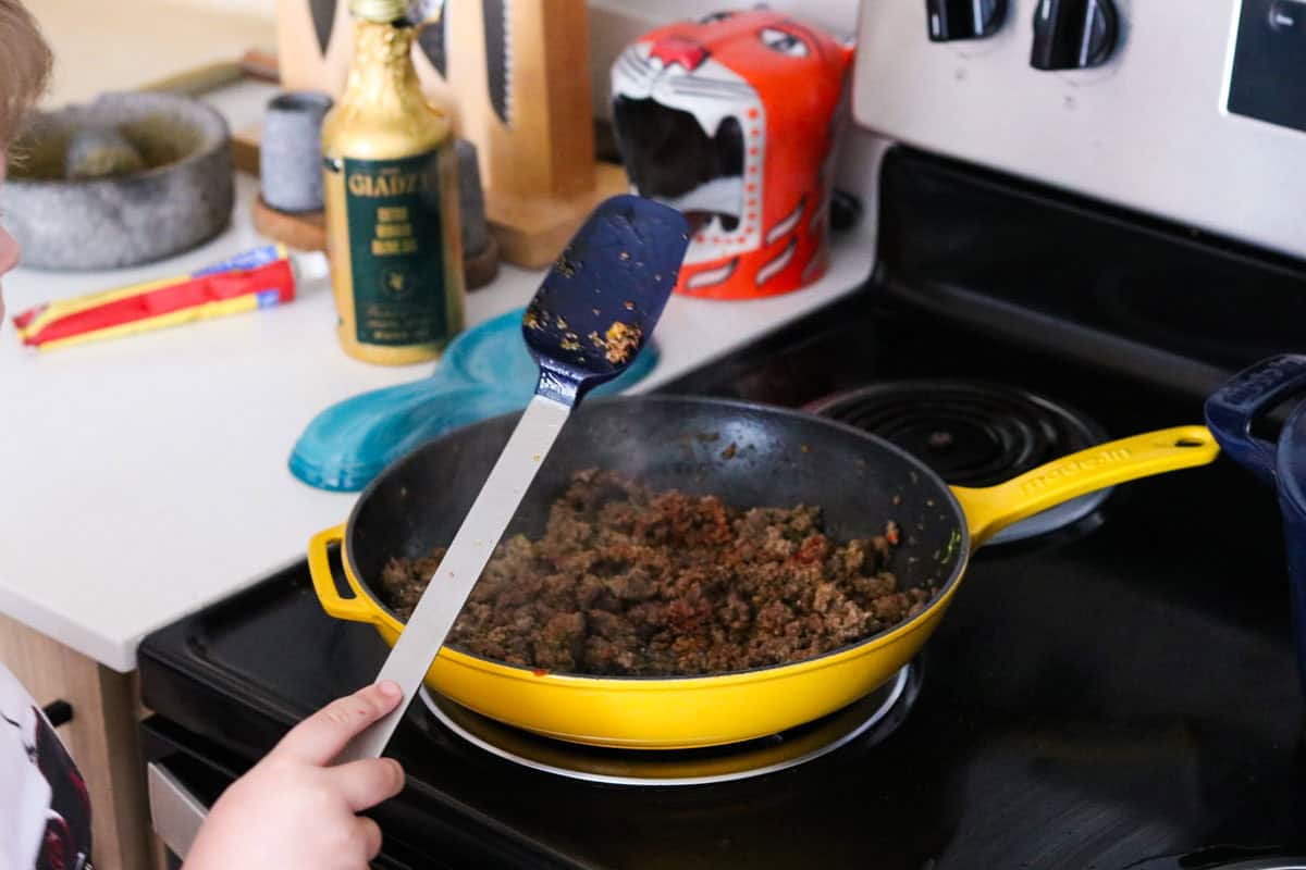 Noah is cooking picadillo in an enameled cast-iron pan