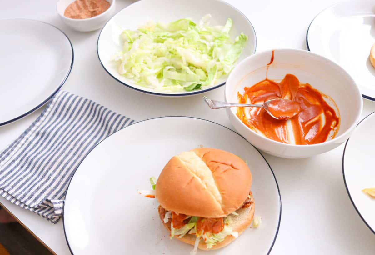 miso-masala fried chicken sando from Mother Tongue beside bowls of toppings
