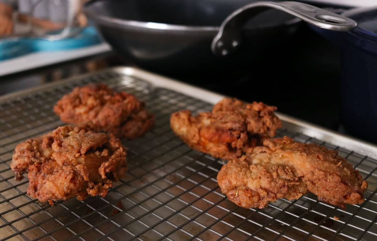 fried chicken on a wire rack over a baking sheet