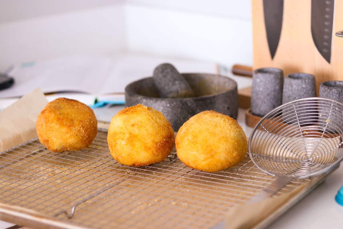 papas rellenas on a drying rack beside a spider strainer