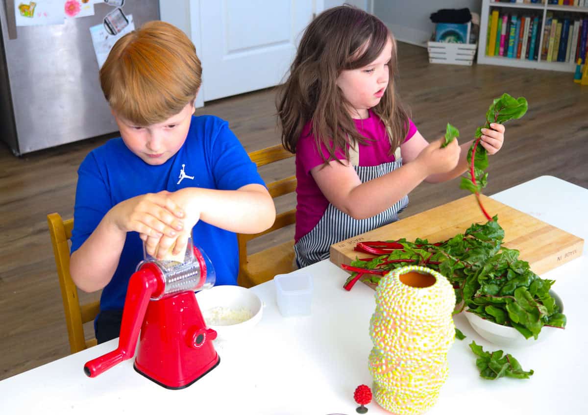 Katalina is tearing the Swiss chard leaves from the stems and Noah is grating pecorino cheese