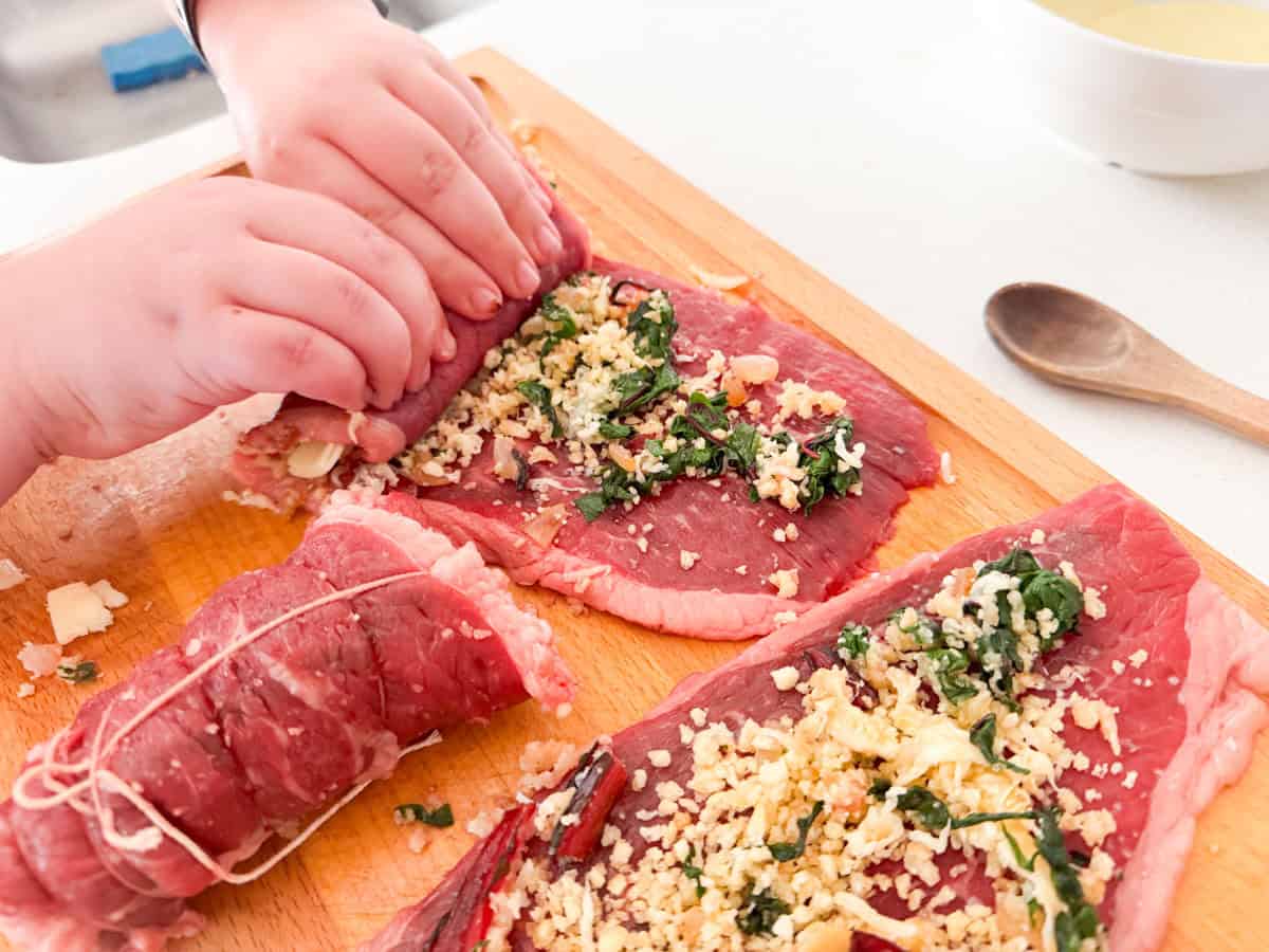 Kaia is rolling up the steak to make braciole