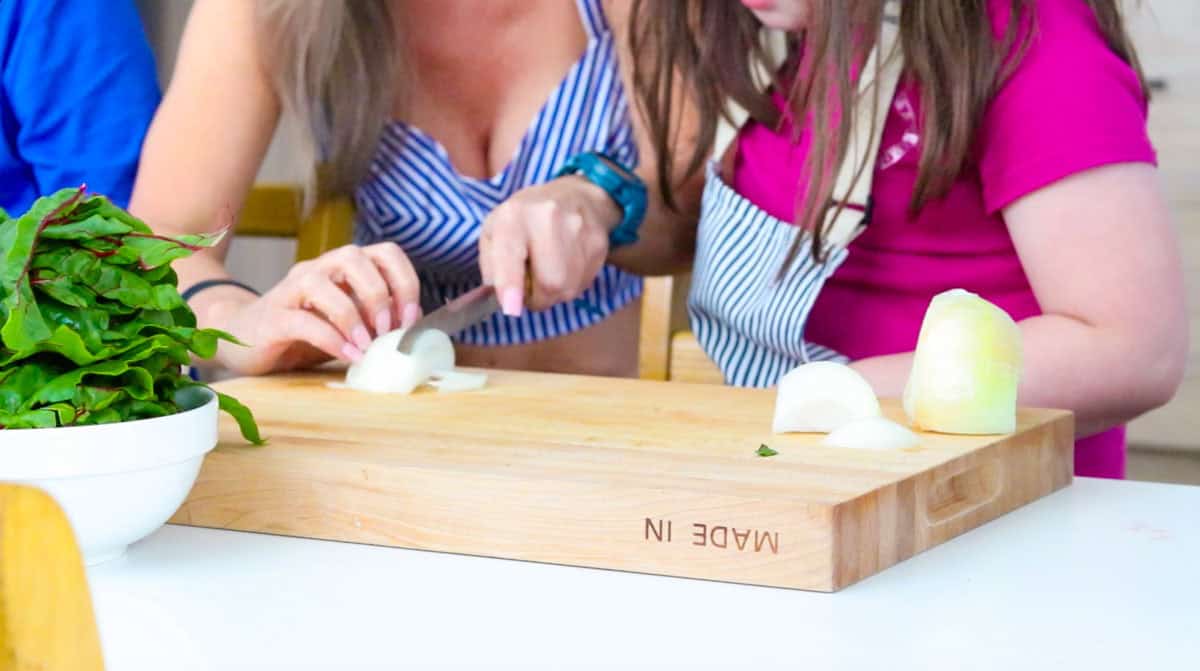 Kristin is showing Katalina how to cut an onion while protecting your fingers