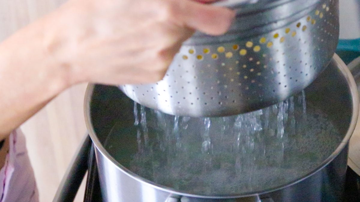 Kristin is lifting the pasta insert with the pappardelle pasta out of the stock pot filled with hot water