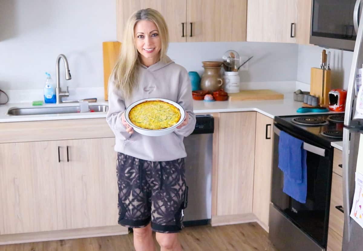 Kristin is showing the camera a baked zucchini casserole before it is broiled