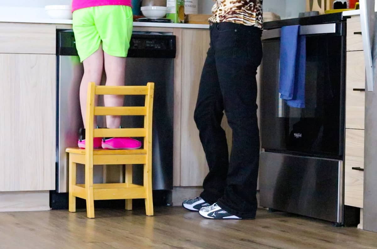 Kat and Kristin are making stracciatella. Kat is standing on a chair at the kitchen counter