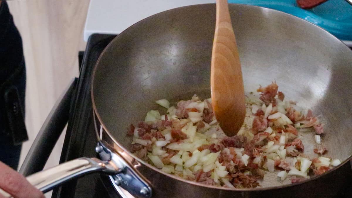 cooking prosciutto, onion, and garlic in a saucier